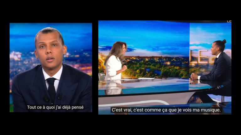 Stromae dévoile un titre inédit en costume cravate au 20h de TF1. Il chante assis au bureau de Anne-Claire Coudray - stromae 1